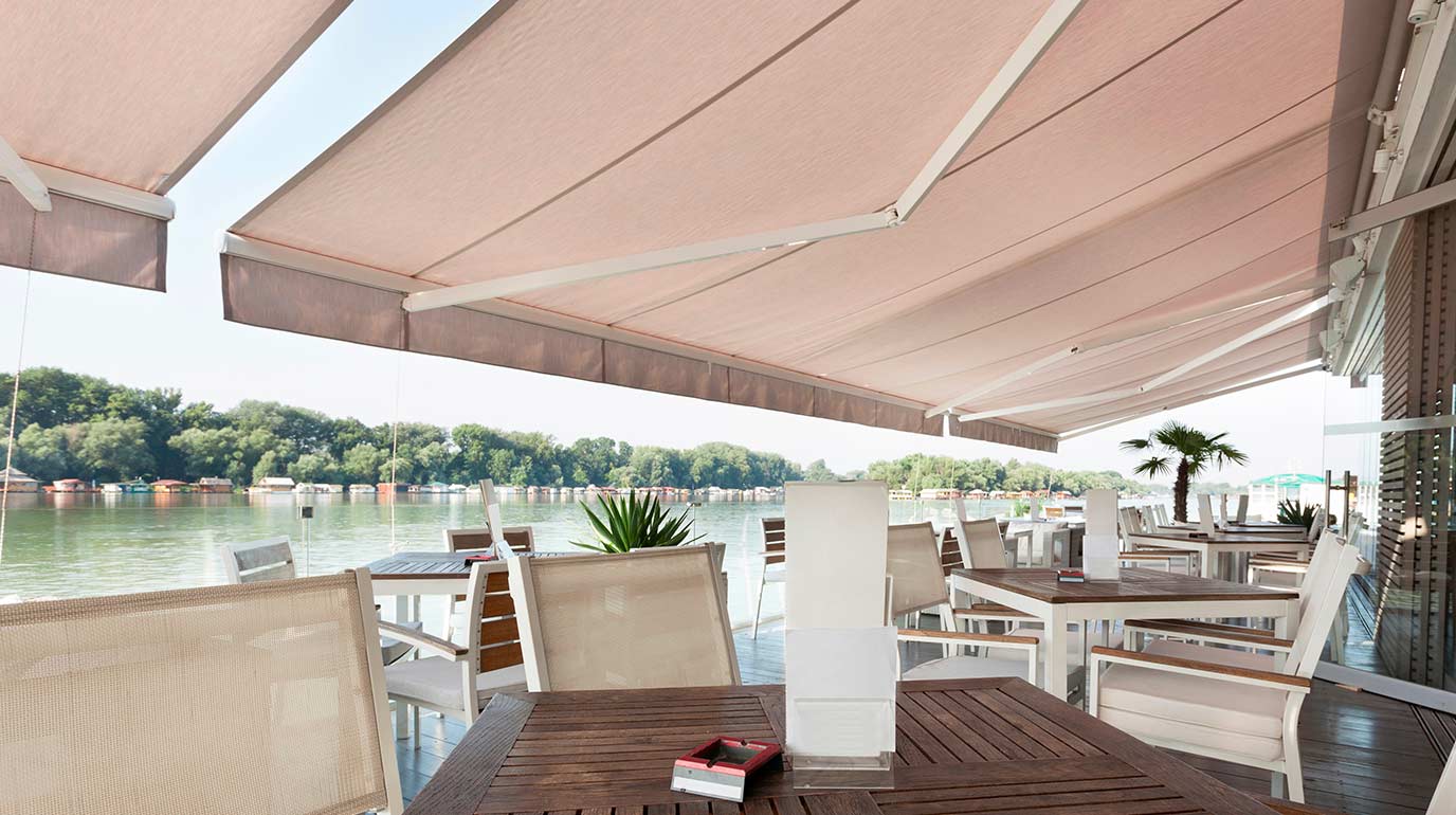 Store banne Sofareb pour la terrasse d'un restaurant proche d'une rivière